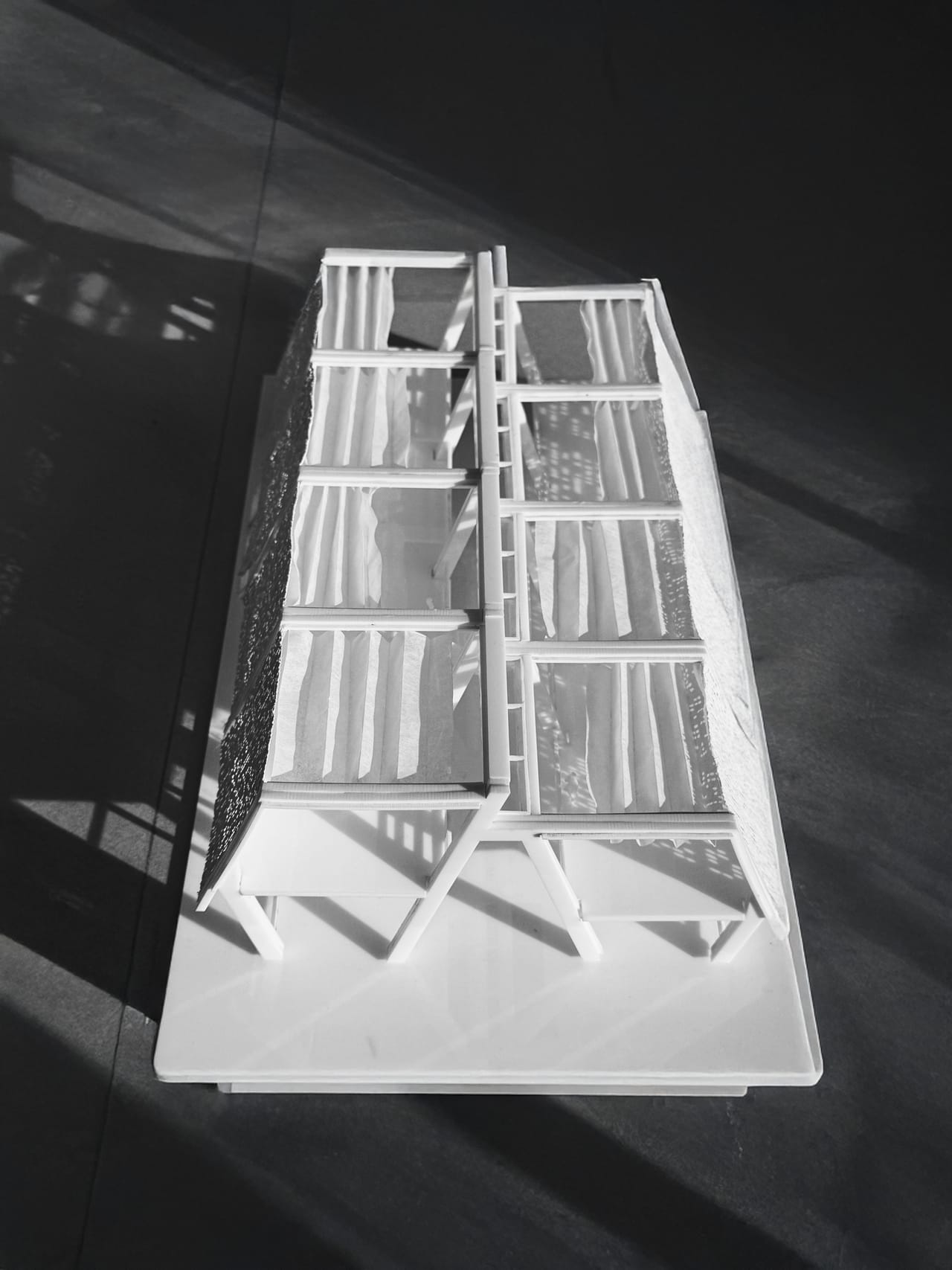 Overhead black-and-white photograph of the white model, showing the row of frames and the floor levels